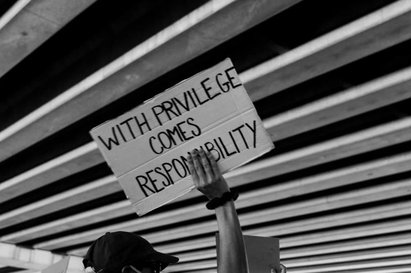 Hand holding a sign saying "With Privilege comes responsibility"
