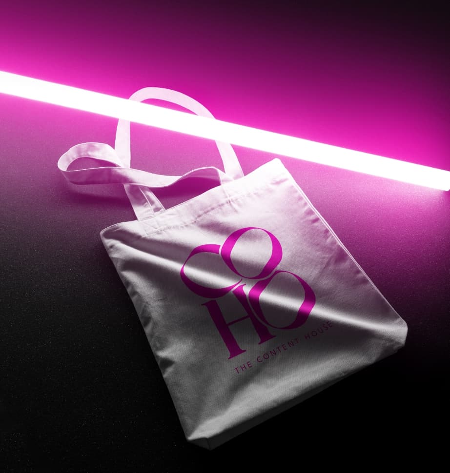 Tote bag mockup featuring the CoHo logo with a pink neon light beside it, designed by Chukster.