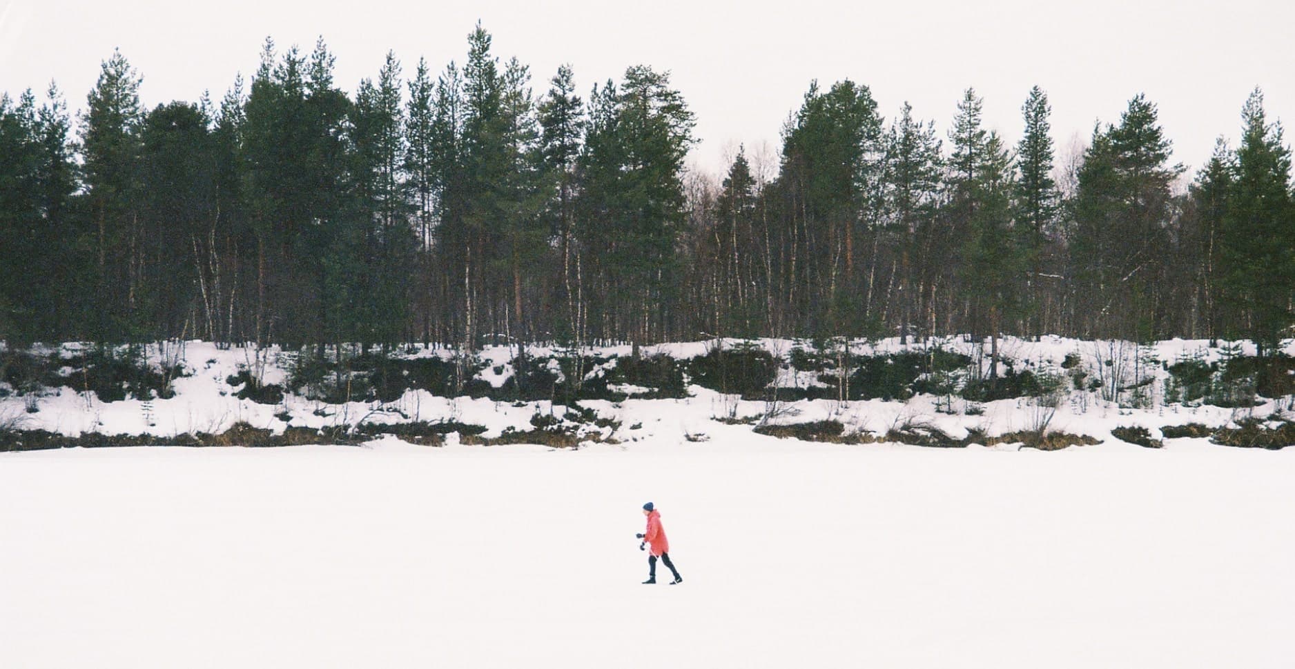 A person walking alone in the middle of a vast snowy landscape in Finland during a digital detox journey.